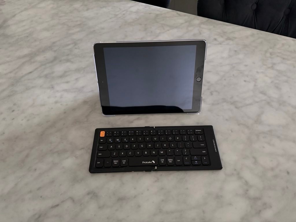 An ipad on a stand and wireless keyboard.